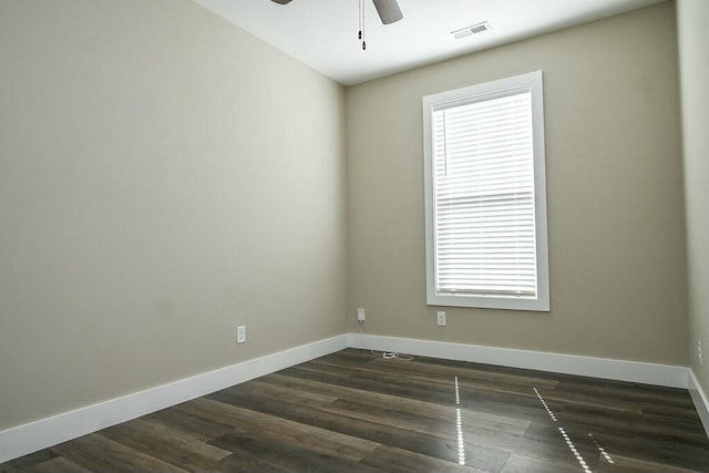 empty room with a ceiling fan, baseboards, visible vents, and dark wood-style flooring