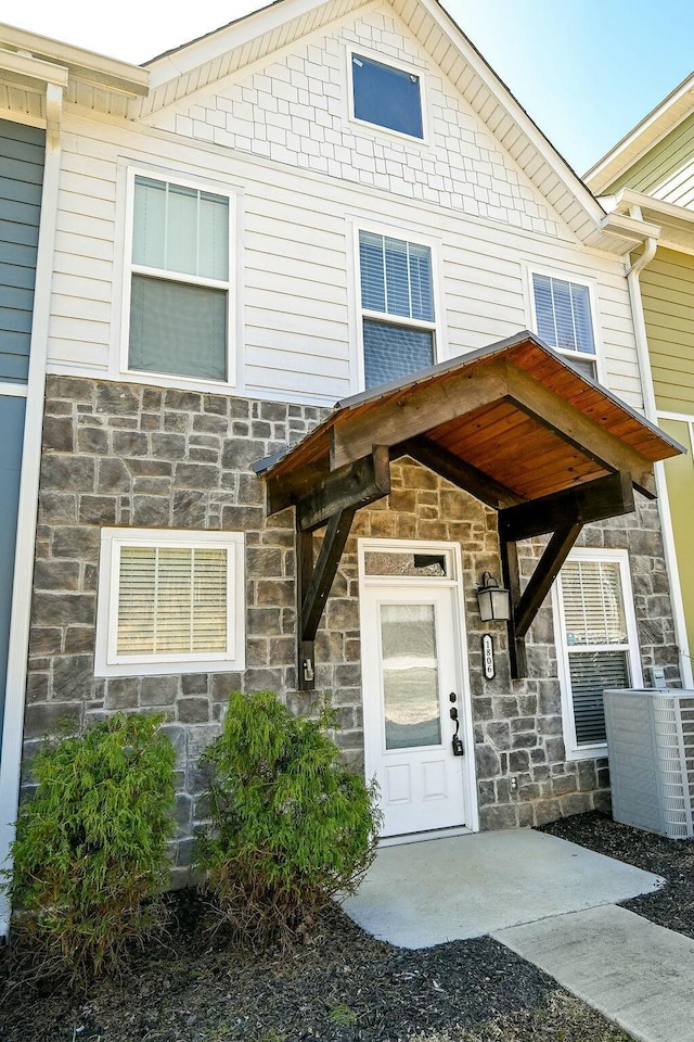 entrance to property with stone siding and central air condition unit