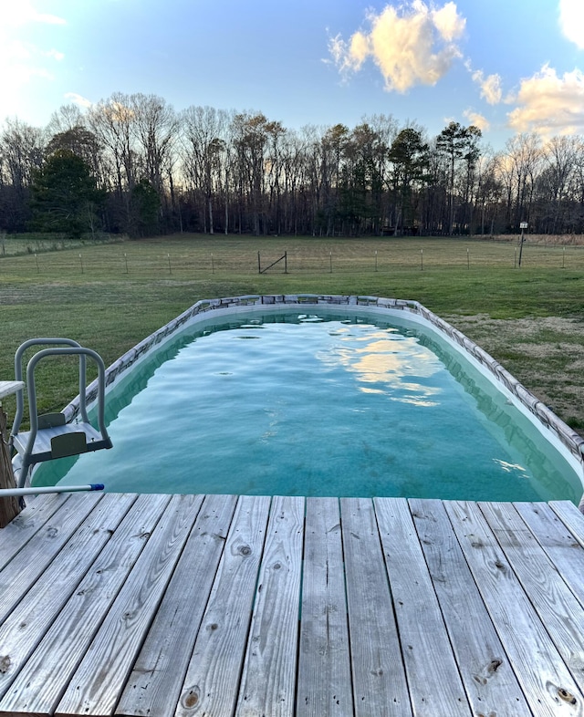 view of swimming pool featuring a wooden deck and a lawn