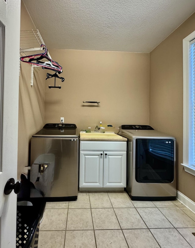 washroom with cabinets, separate washer and dryer, light tile patterned floors, and a textured ceiling