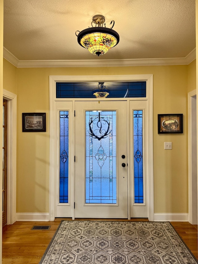 entrance foyer with crown molding, wood-type flooring, and a textured ceiling