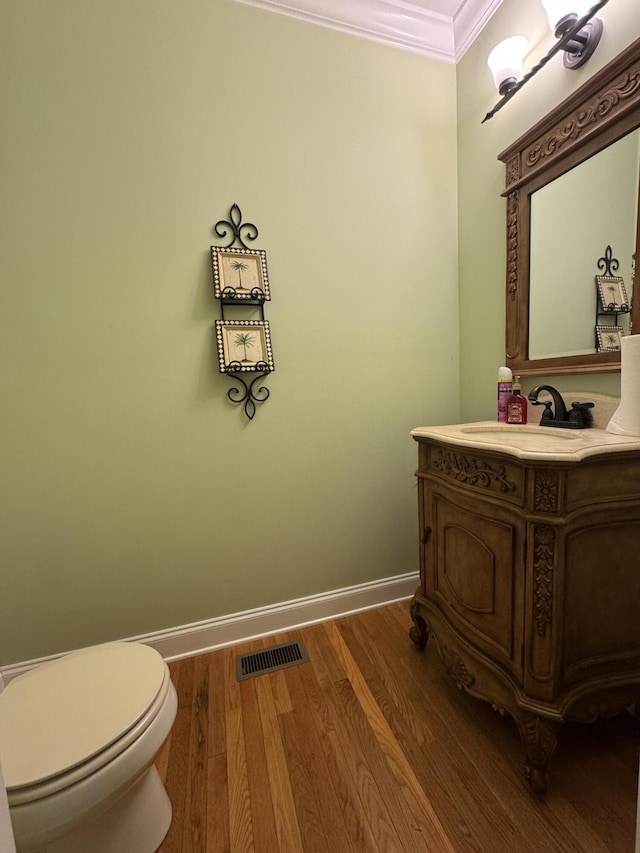 bathroom with vanity, crown molding, wood-type flooring, and toilet