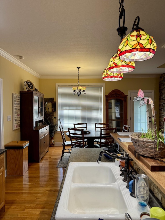 kitchen with crown molding, sink, a chandelier, and hardwood / wood-style floors