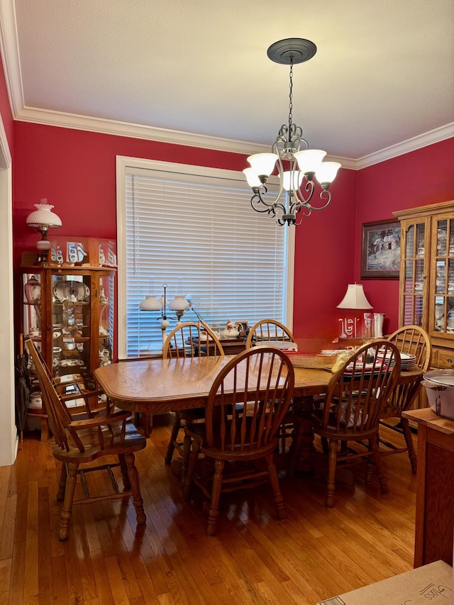 dining room with wood-type flooring, ornamental molding, and a chandelier