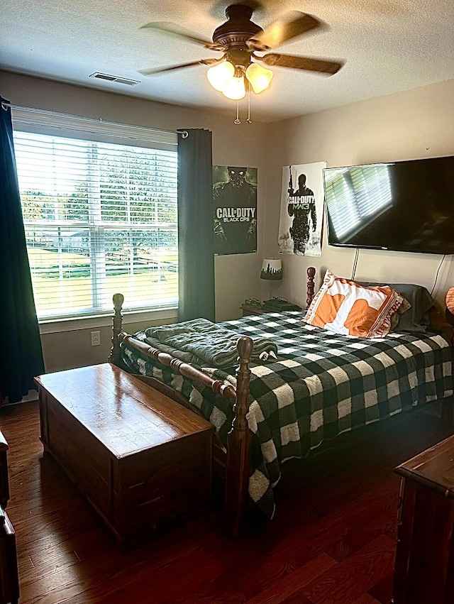 bedroom featuring dark wood-type flooring, a textured ceiling, and ceiling fan