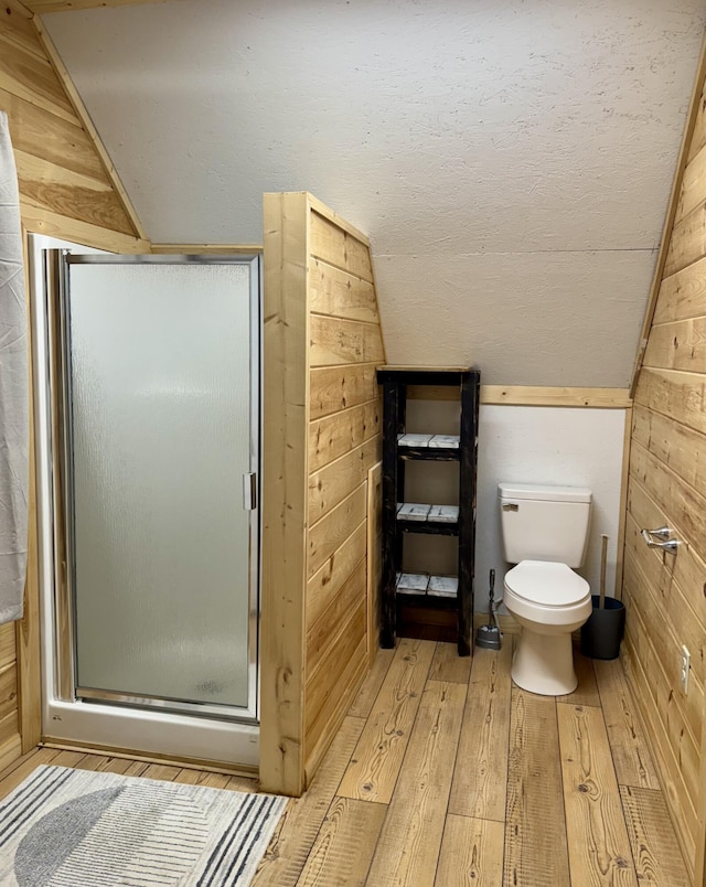 bathroom with a shower with door, lofted ceiling, hardwood / wood-style floors, and wooden walls