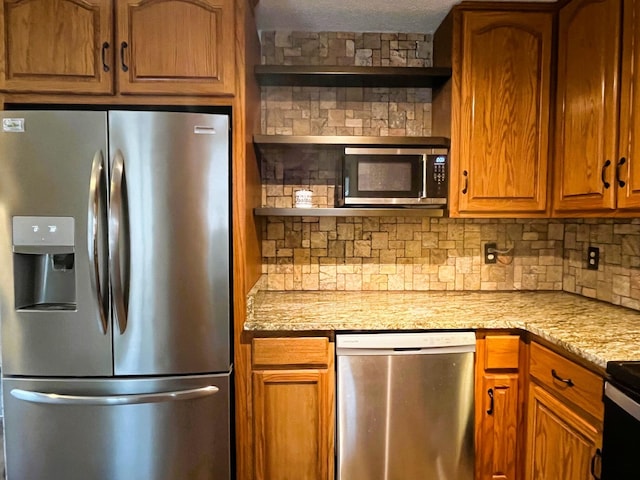 kitchen with tasteful backsplash, light stone countertops, and appliances with stainless steel finishes