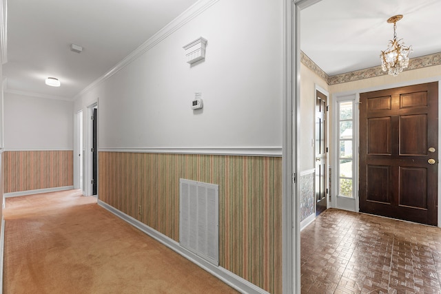 entryway featuring a notable chandelier, carpet floors, and crown molding