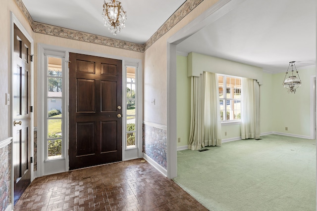 carpeted entryway featuring a wealth of natural light and an inviting chandelier