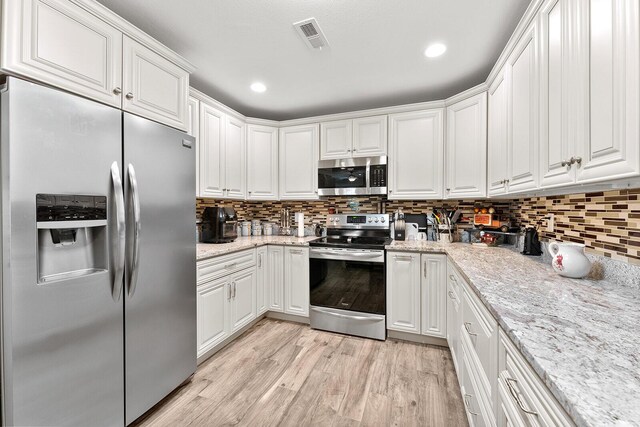407 Kahite Trl, Vonore, TN 37885 - kitchen with appliances with stainless steel finishes, white cabinets, decorative backsplash, light wood finished floors, and recessed lighting