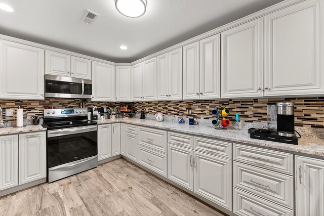 407 Kahite Trl, Vonore, TN 37885 - kitchen with stainless steel appliances, white cabinetry, decorative backsplash, and light stone countertops