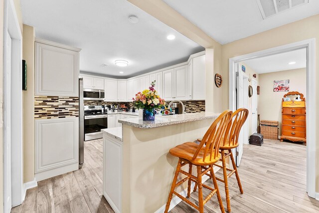 407 Kahite Trl, Vonore, TN 37885 - kitchen with appliances with stainless steel finishes, a peninsula, light wood-style floors, decorative backsplash, and recessed lighting