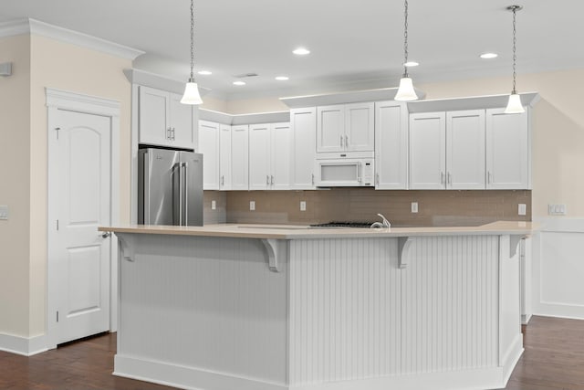 kitchen featuring pendant lighting, a breakfast bar area, high end fridge, white cabinetry, and a center island with sink