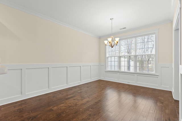 spare room featuring crown molding, dark wood-type flooring, and a notable chandelier