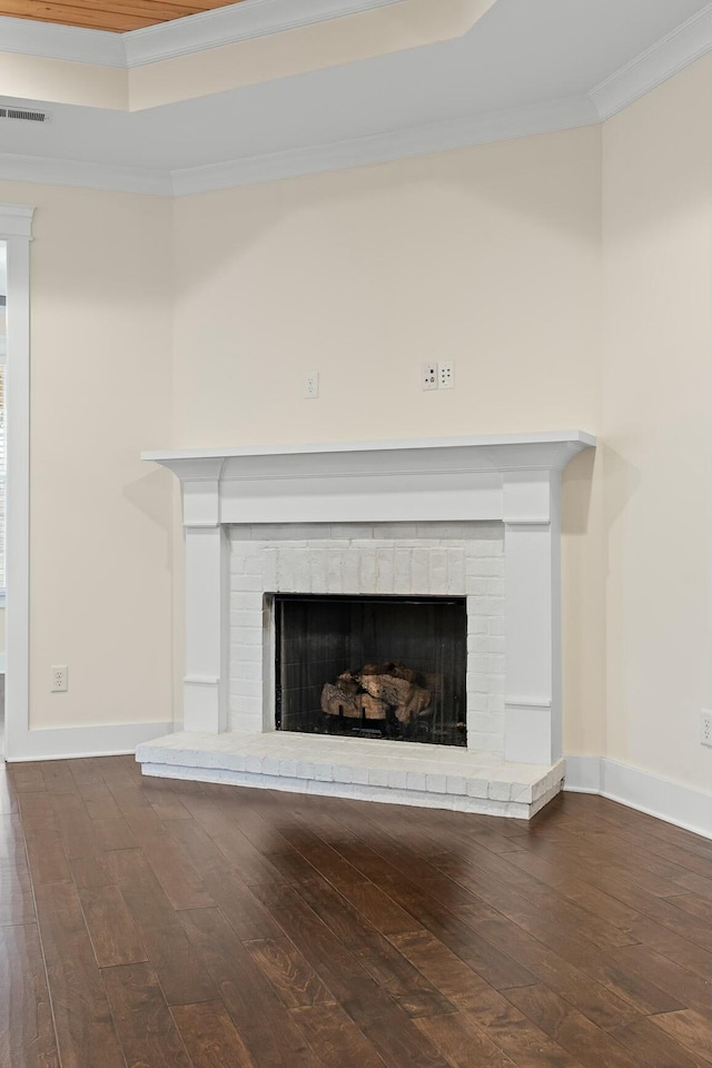 room details featuring crown molding, a raised ceiling, hardwood / wood-style floors, and a brick fireplace