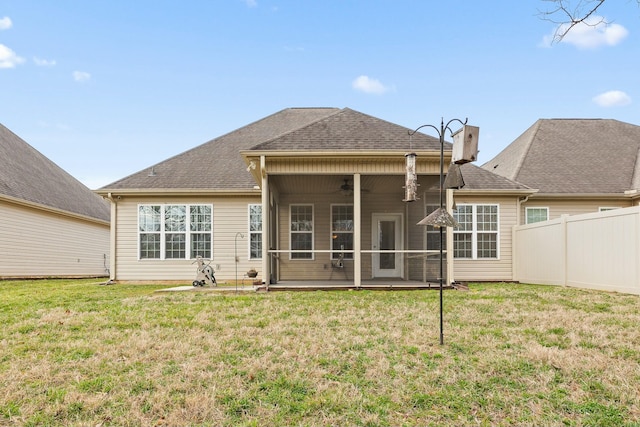 back of property featuring ceiling fan and a yard