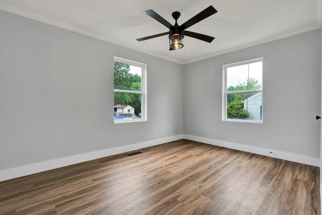 empty room with wood finished floors, a ceiling fan, baseboards, and ornamental molding