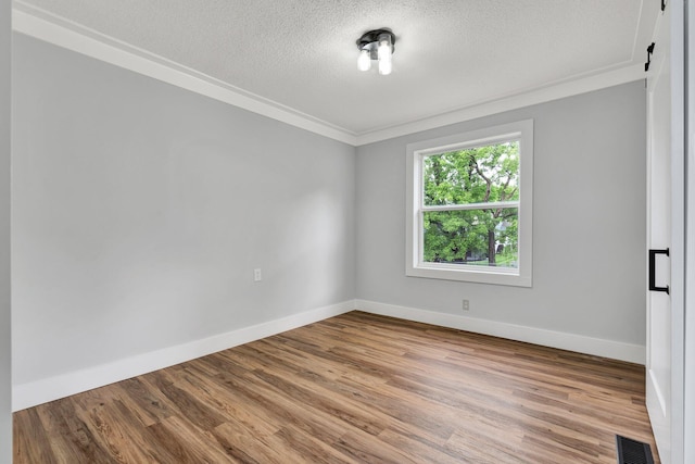 unfurnished room with a textured ceiling, baseboards, ornamental molding, and visible vents