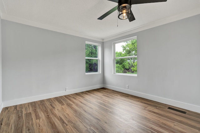 spare room featuring baseboards, visible vents, a ceiling fan, wood finished floors, and ornamental molding