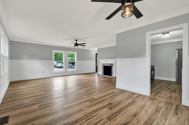 unfurnished living room featuring ceiling fan, a wainscoted wall, wood finished floors, and visible vents