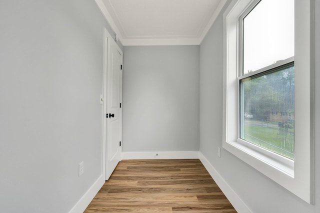 empty room featuring baseboards, crown molding, and wood finished floors