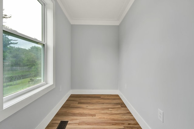 unfurnished room with baseboards, visible vents, light wood-style floors, and crown molding