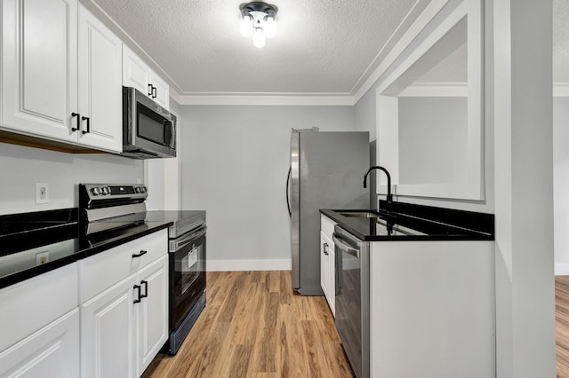 kitchen featuring dark countertops, light wood-style floors, appliances with stainless steel finishes, and a sink