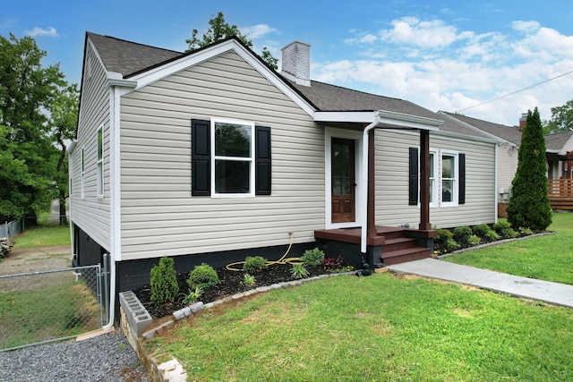 bungalow-style home with a chimney, fence, roof with shingles, and a front yard