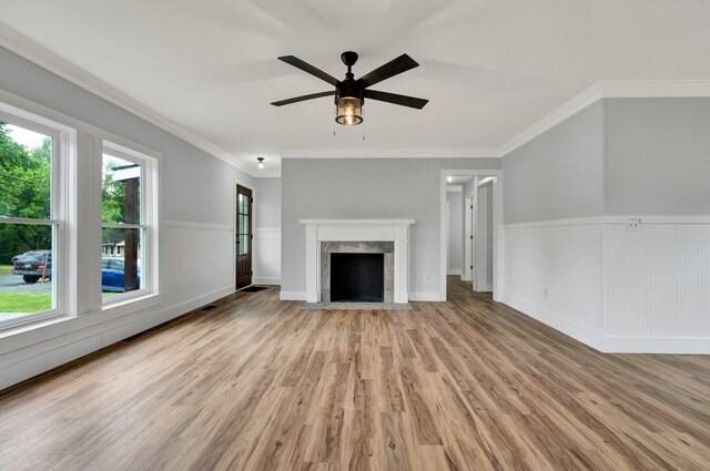 unfurnished living room featuring ceiling fan, ornamental molding, wood finished floors, and a fireplace