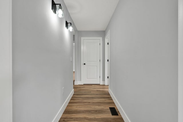 hall featuring wood finished floors, visible vents, and baseboards