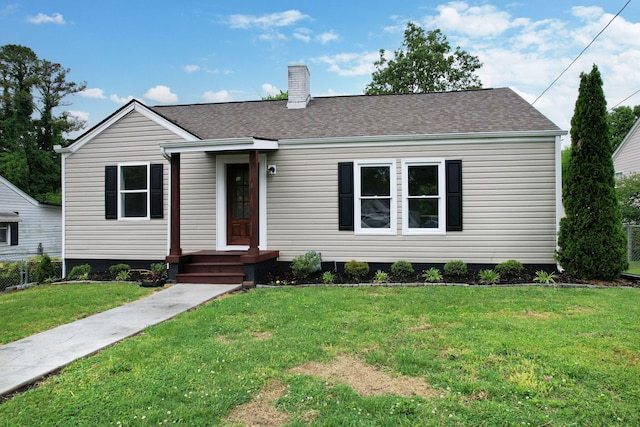 ranch-style home with a front lawn, a chimney, and roof with shingles