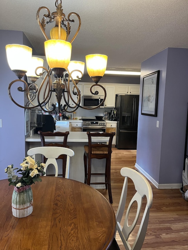 3722 Lockerbie Ln, Powder Springs, GA 30127 - dining area with a textured ceiling, wood finished floors, an inviting chandelier, and baseboards