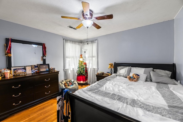 bedroom with ceiling fan, a textured ceiling, and light hardwood / wood-style flooring