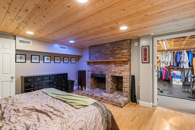 bedroom featuring light hardwood / wood-style floors, a brick fireplace, a closet, and wood ceiling