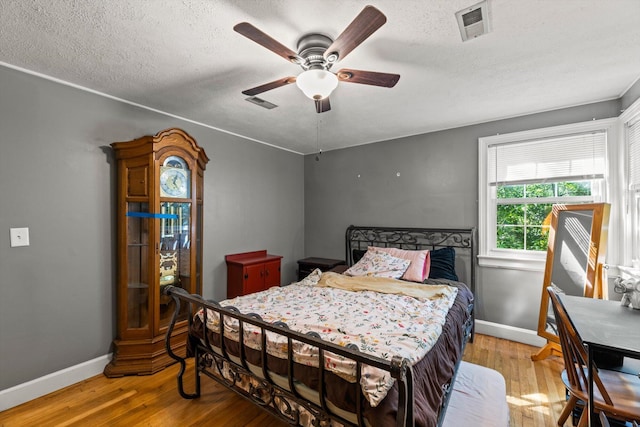 bedroom with ceiling fan, light hardwood / wood-style floors, and a textured ceiling