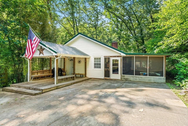 back of house featuring a wooden deck, a sunroom, and a patio