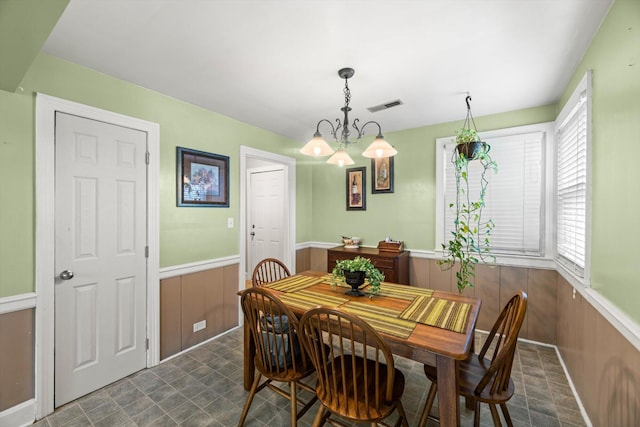 dining area featuring wood walls and an inviting chandelier