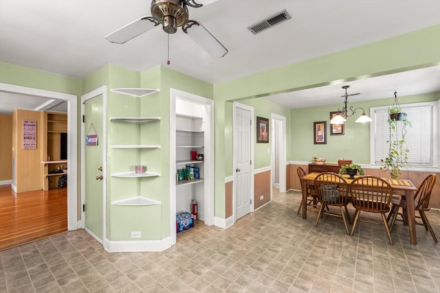 dining room with built in features, hardwood / wood-style floors, and ceiling fan with notable chandelier