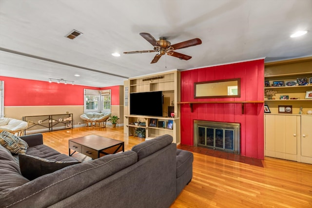 living room with ceiling fan, a fireplace, and wood-type flooring