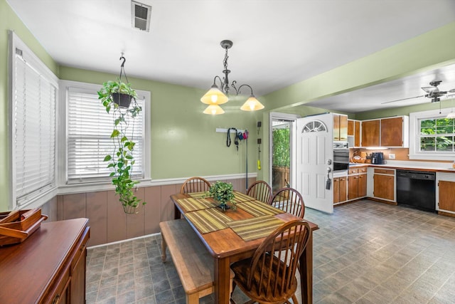 dining space with wood walls and ceiling fan with notable chandelier