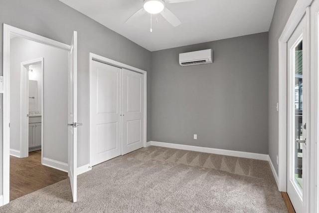 unfurnished bedroom with a closet, carpet floors, a wall unit AC, and ceiling fan