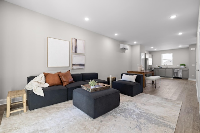 living area featuring a wall unit AC, light wood-style flooring, baseboards, and recessed lighting