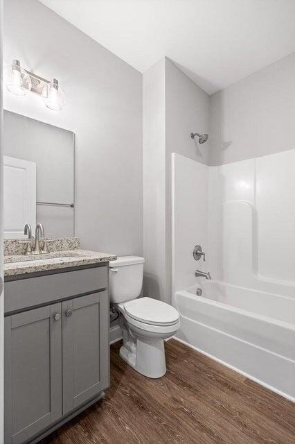 full bathroom featuring hardwood / wood-style floors, shower / tub combination, vanity, and toilet