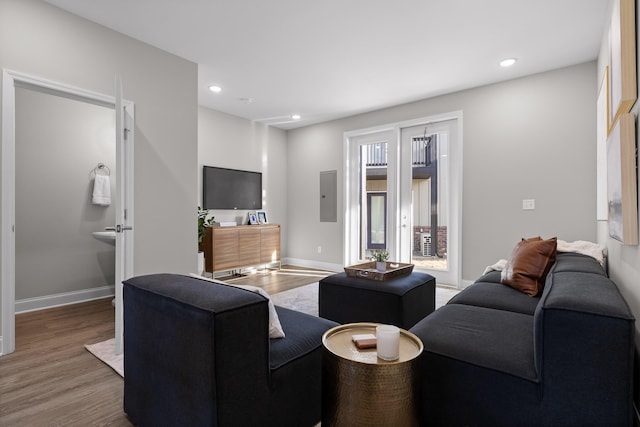 living area featuring electric panel, baseboards, and wood finished floors