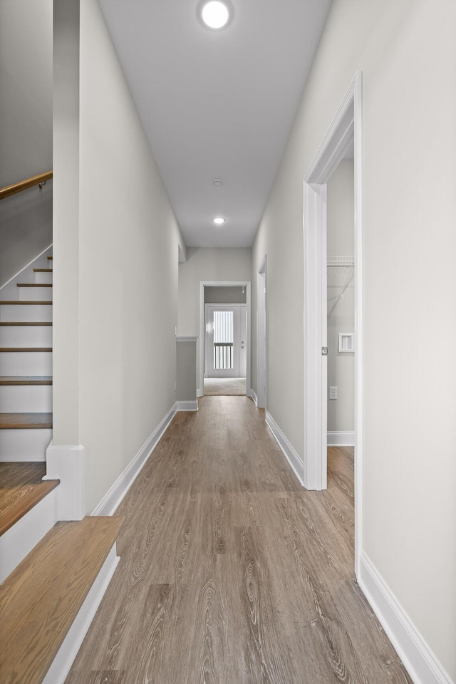 corridor featuring stairs, wood finished floors, and baseboards