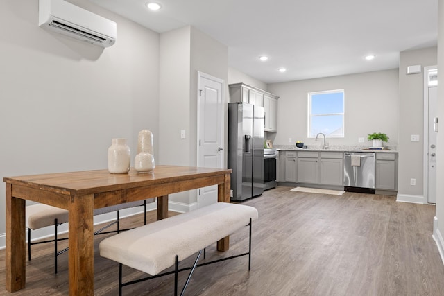 kitchen with a wall unit AC, light wood-style flooring, recessed lighting, appliances with stainless steel finishes, and gray cabinets