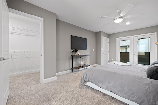 bedroom with ceiling fan, light colored carpet, baseboards, a spacious closet, and french doors