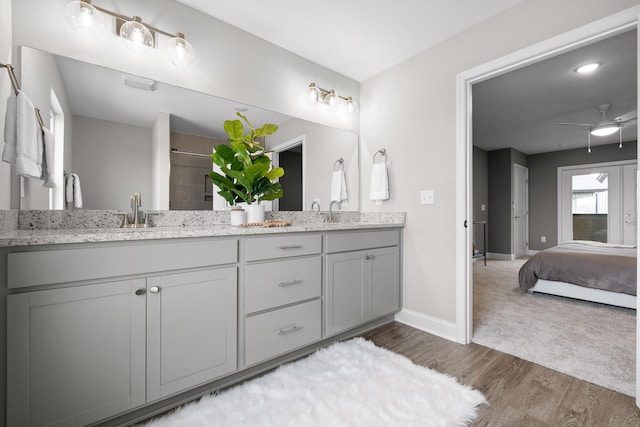 ensuite bathroom with wood finished floors, a ceiling fan, baseboards, a shower, and double vanity