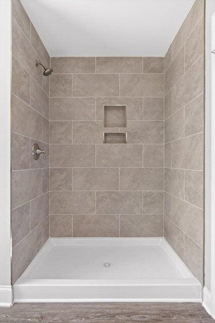 bathroom with hardwood / wood-style flooring and a tile shower