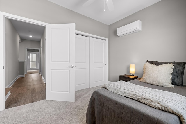 carpeted bedroom featuring a closet, ceiling fan, baseboards, and a wall mounted AC